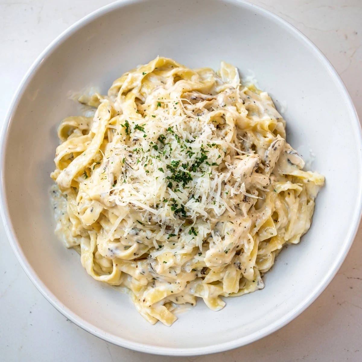 Enjoy a steaming bowl of The Perfect 20-Minute Creamy Alfredo Pasta topped with fresh parsley and cheese.