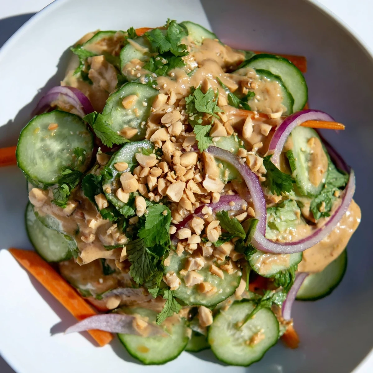 Creamy Thai-Style Peanut Cucumber Salad, showcasing crunchy cucumbers and carrots, drizzled with peanut dressing.