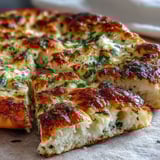 Golden-brown The Best Easy Garlic Naan Bread served warm alongside a bowl of chicken curry.