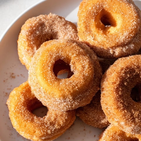 Golden-brown, air fryer donuts coated in cinnamon sugar, ready to enjoy this easy American dessert.