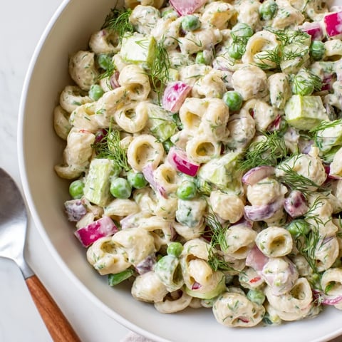 Bright green peas and crisp dill pickles coat ditalini pasta in a creamy dressing, ready for a spring potluck.