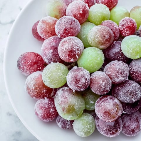 A close-up of vibrant, jewel-toned frozen grapes, ready to burst with sweet, cold flavor.