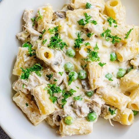 A close-up shot of a bubbling slow cooker Chicken Alfredo pasta bake, full of cheesy goodness and pasta.
