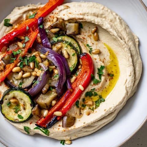 Vibrant Hummus Roasted Veggies: Serving suggestion of a platter ready to savor, with golden pine nuts and parsley.