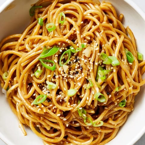 A close-up of an Asian Garlic Noodle Bowl showing glossy noodles with julienned carrots and bean sprouts