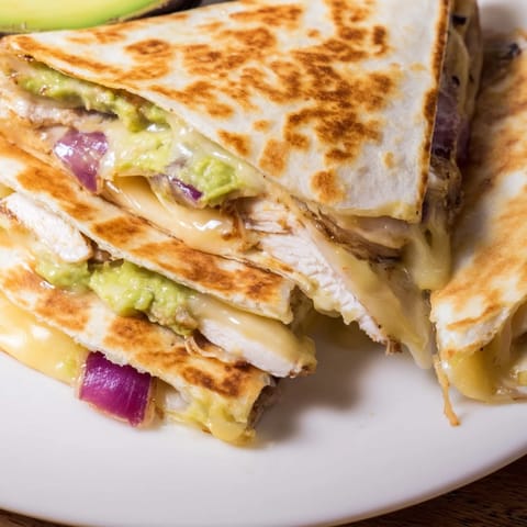 Inside the cheesy Chicken Avocado Quesadilla, creamy avocado mash and grilled chicken are visible.