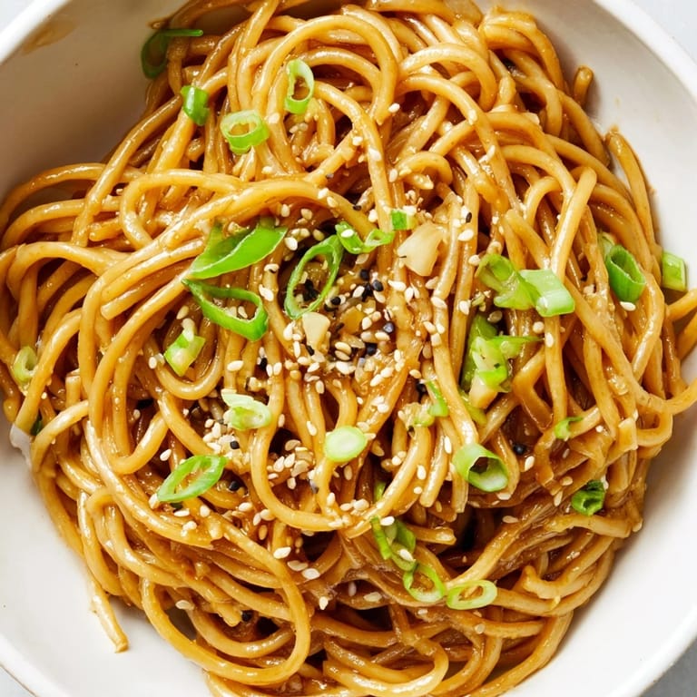 A close-up of an Asian Garlic Noodle Bowl showing glossy noodles with julienned carrots and bean sprouts