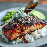 Glazed teriyaki salmon bowl with fluffy rice, edamame, and cucumber.